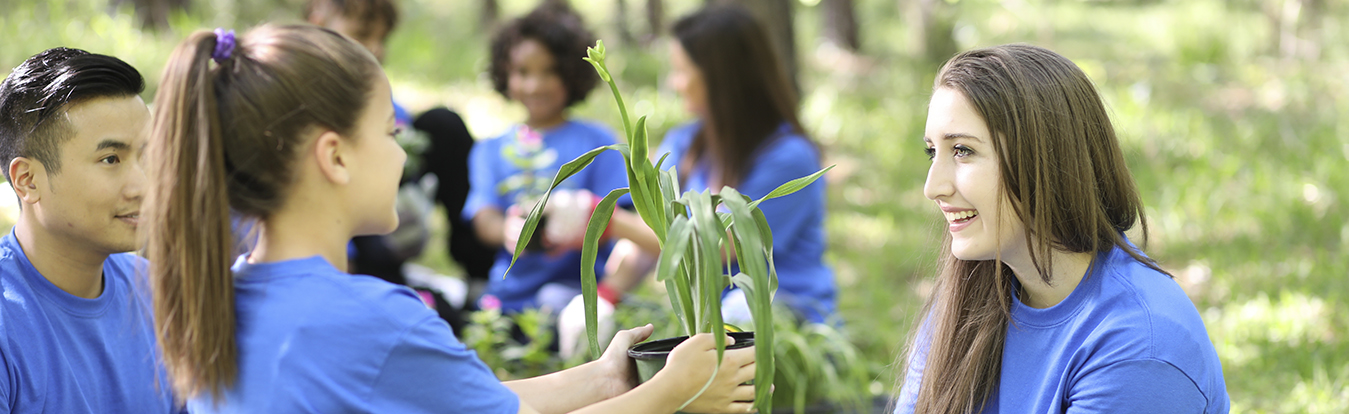 A girl hands a plant to a woman during a volunteer event.